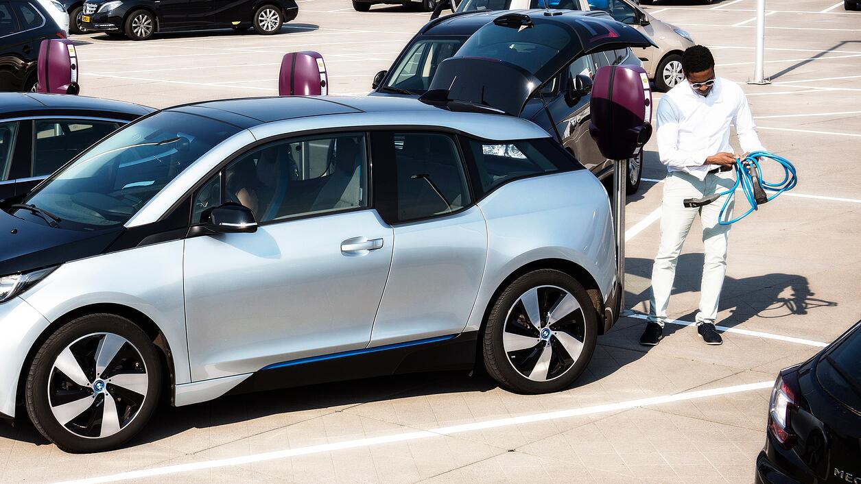 Un client chez un concessionnaire tenant des câbles de recharge pour voitures électriques.