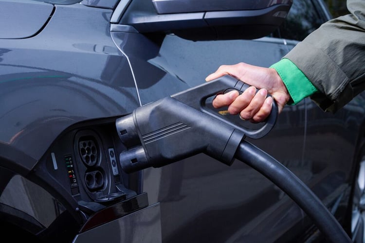 A DC charger being plugged into a black electric car.