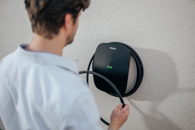 A man wearing a blue shirt hanging back his cable on the EVBox Livo.