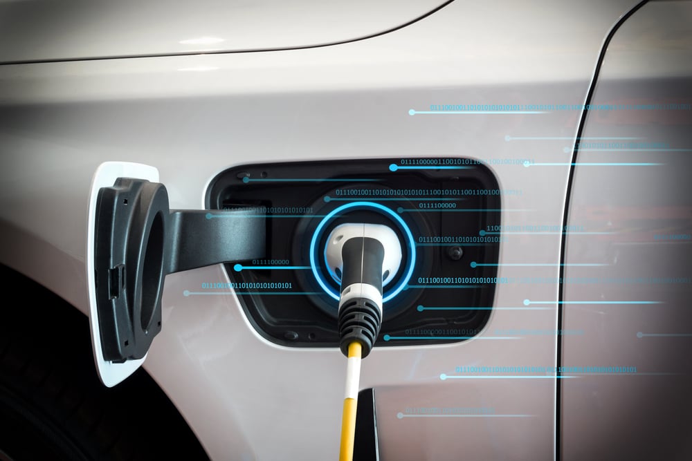 A futuristic photo of charging cable plugged in an electric car while showing charging data flowing.