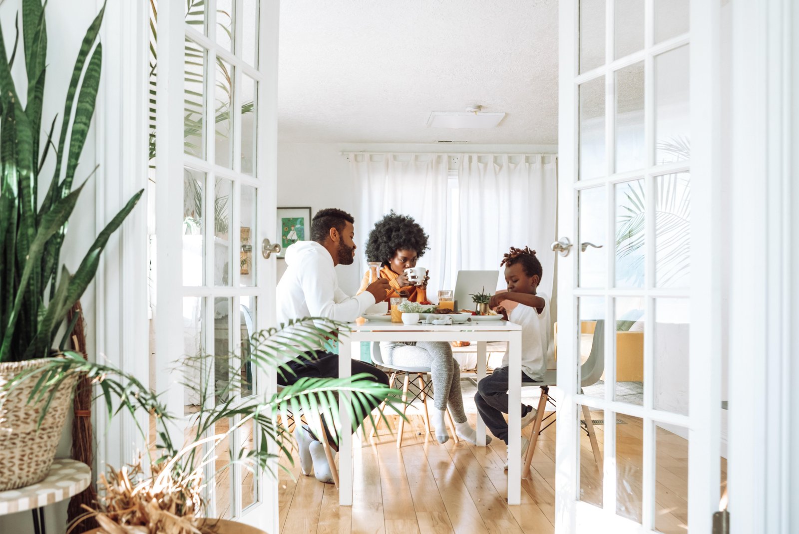 A young family sitting at their dining room table having breakfast whilst the electric vehicle is sitting in their garage, fully charged.