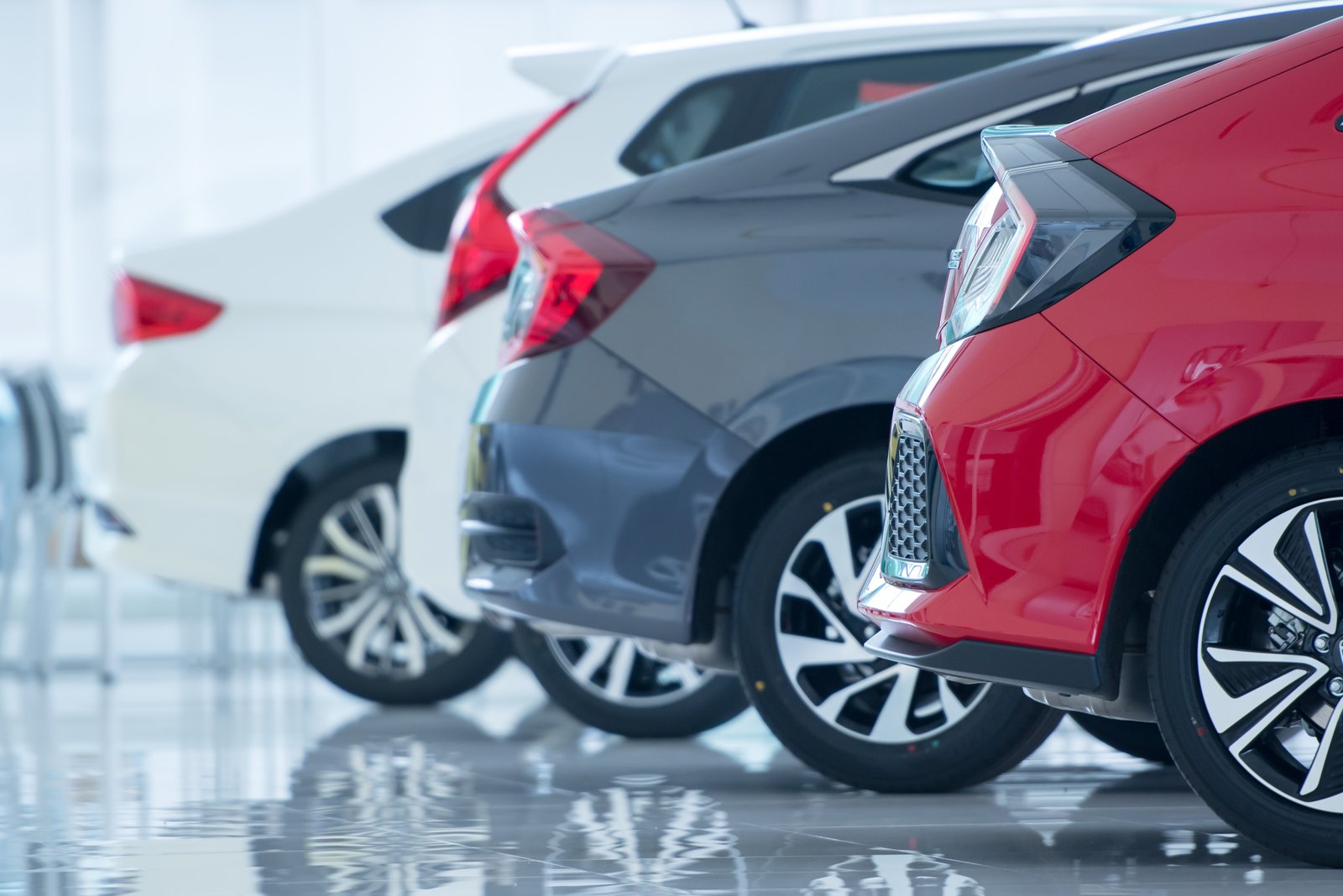 A closeup of four modern cars parked in a showroom.