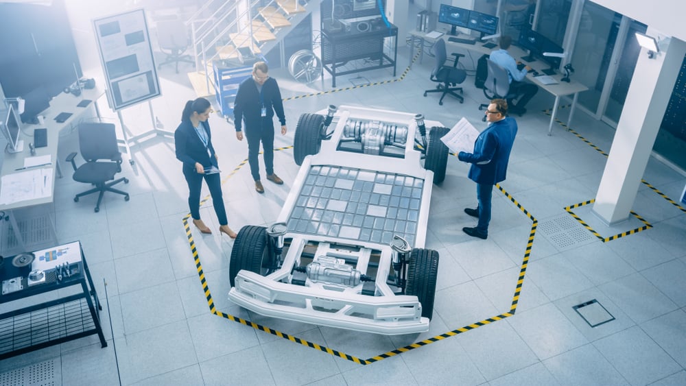 Engineers looking at the EV battery on a bare electric car.