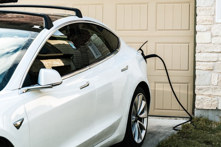 A closeup of a car charging at home outside a garage.