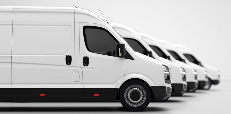 A professional photograph of several parked white light commercial vehicles with a plain background.