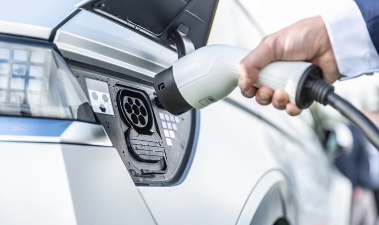 A closeup of a charging plug while a person is connecting an electric car to charge